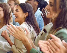 Image shows multiple employees clapping and smiling in the same direction.